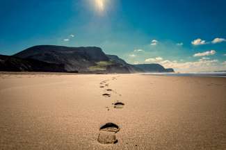 Fußabdrücke im feinen Sand eines hübschen Strandes.