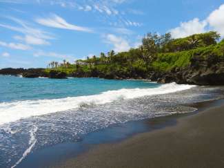 Verweilen Sie am schwarzen Sandstrand auf Maui.